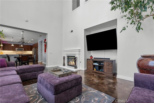 29259 Black Pine Way, Saugus, CA 91390 - living area with concrete flooring, baseboards, a glass covered fireplace, a towering ceiling, and a chandelier