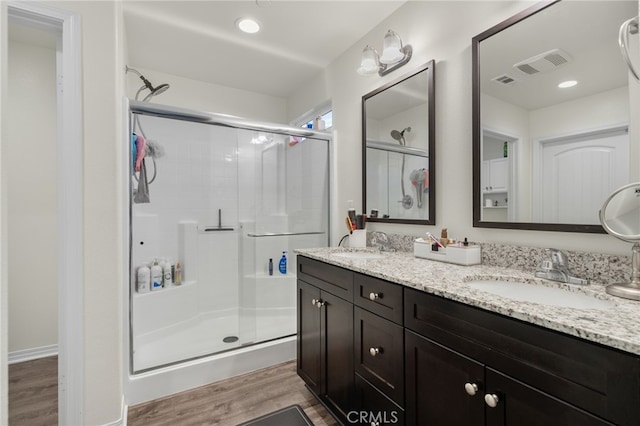 14226 Bonavento Ln, Beaumont, CA 92223 - bathroom featuring wood finished floors, a shower stall, and double vanity