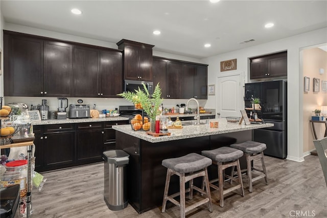 14226 Bonavento Ln, Beaumont, CA 92223 - kitchen with freestanding refrigerator, stainless steel microwave, a sink, light wood finished floors, and recessed lighting
