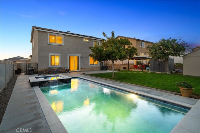 14226 Bonavento Ln, Beaumont, CA 92223 - back of property at dusk featuring a pool with connected hot tub, a patio area, and stucco siding