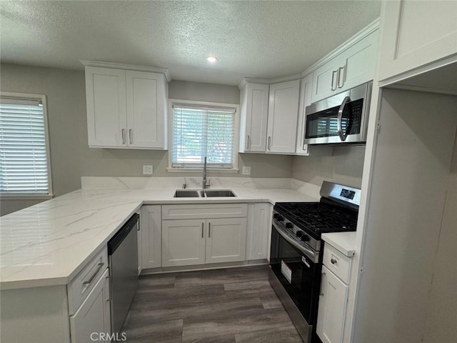 8667 Colorado Ave, Riverside, CA 92504 - kitchen with appliances with stainless steel finishes, a sink, a textured ceiling, a peninsula, and white cabinetry