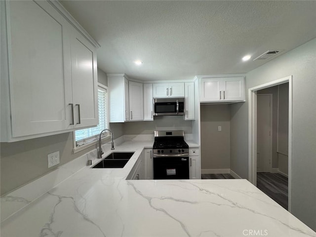 8667 Colorado Ave, Riverside, CA 92504 - kitchen featuring appliances with stainless steel finishes, a sink, white cabinets, light stone counters, and recessed lighting