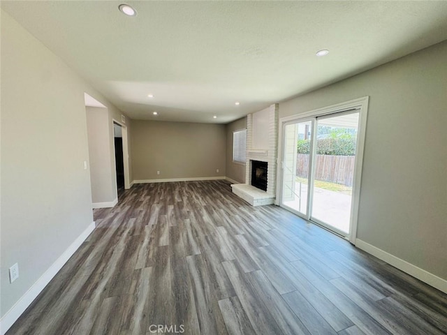 8667 Colorado Ave, Riverside, CA 92504 - unfurnished living room with dark wood-style flooring, baseboards, recessed lighting, and a brick fireplace