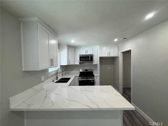 8667 Colorado Ave, Riverside, CA 92504 - kitchen featuring appliances with stainless steel finishes, a sink, light stone counters, a peninsula, and a textured ceiling