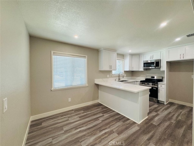 8667 Colorado Ave, Riverside, CA 92504 - kitchen with appliances with stainless steel finishes, dark wood-style floors, a peninsula, white cabinets, and light countertops