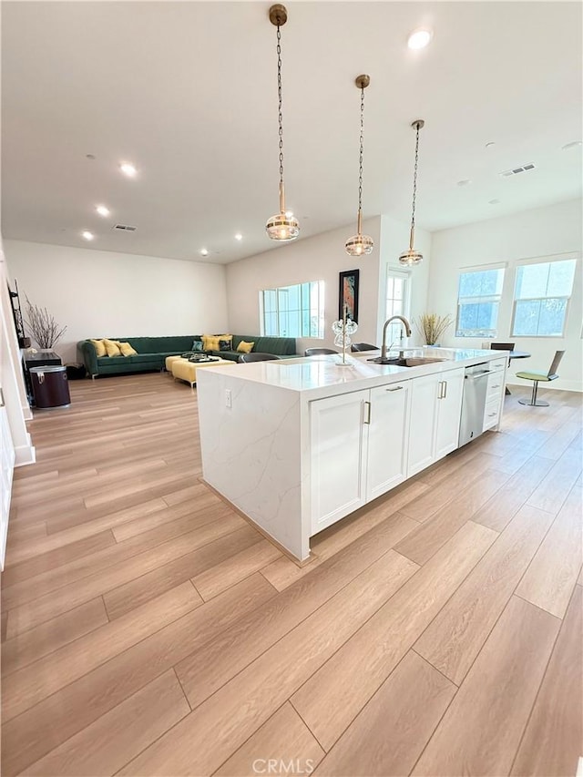 8896 Los Coyotes Ct Unit 410, Buena Park, CA 90621 - kitchen featuring a sink, light wood finished floors, a kitchen island with sink, white cabinetry, and open floor plan