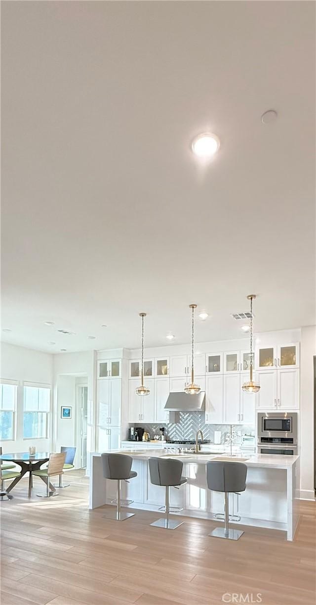 8896 Los Coyotes Ct Unit 410, Buena Park, CA 90621 - kitchen with a breakfast bar, stainless steel microwave, tasteful backsplash, light countertops, and white cabinetry