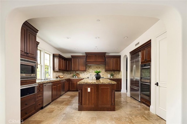 47 Via Alcamo, San Clemente, CA 92673 - kitchen featuring built in appliances, tasteful backsplash, arched walkways, a center island, and dark brown cabinetry