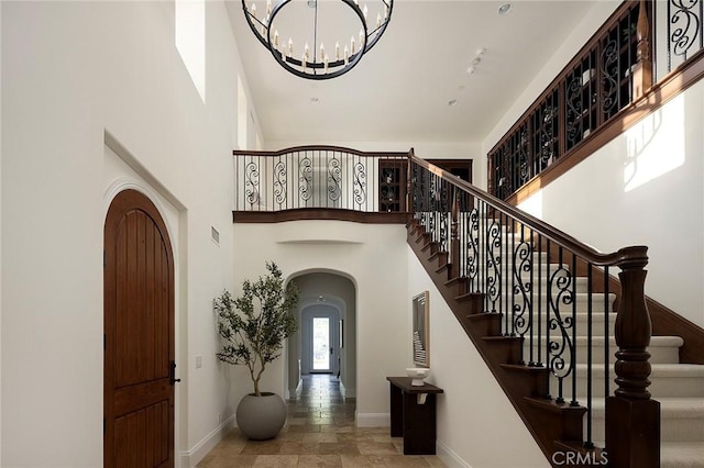 47 Via Alcamo, San Clemente, CA 92673 - staircase with arched walkways, baseboards, a towering ceiling, stone tile floors, and a chandelier