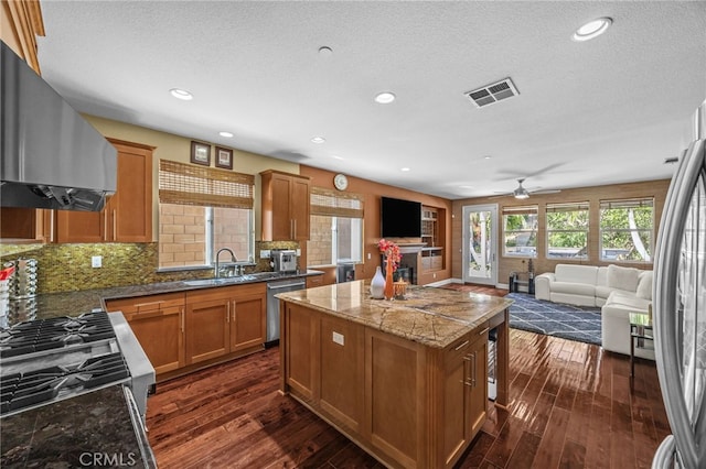 4267 Carnegie Ct, Riverside, CA 92505 - kitchen with wall chimney exhaust hood, appliances with stainless steel finishes, open floor plan, a kitchen island, and dark wood finished floors