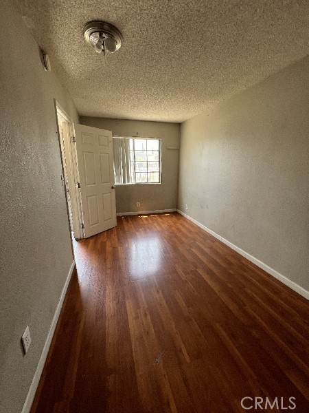 13753 Los Angeles St, Baldwin Park, CA 91706 - spare room with wood finished floors, baseboards, a textured ceiling, and a textured wall