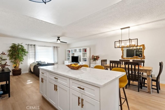609 S Palm Ave Unit B, Hemet, CA 92543 - kitchen featuring light wood-style floors, a kitchen island, white cabinetry, open floor plan, and a breakfast bar area