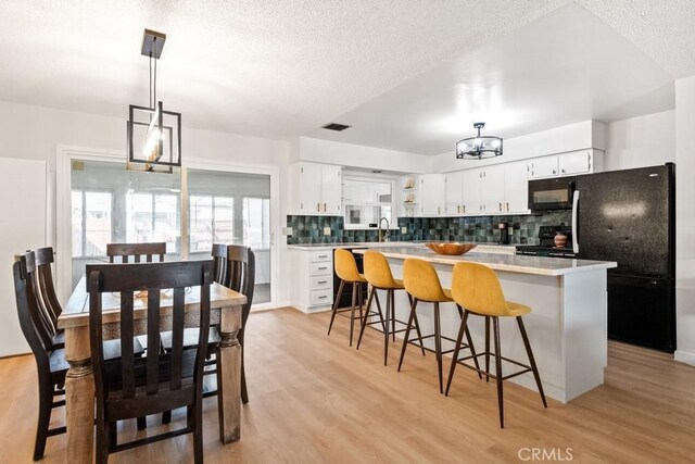 609 S Palm Ave Unit B, Hemet, CA 92543 - kitchen featuring black appliances, white cabinets, decorative backsplash, a kitchen island, and light wood finished floors