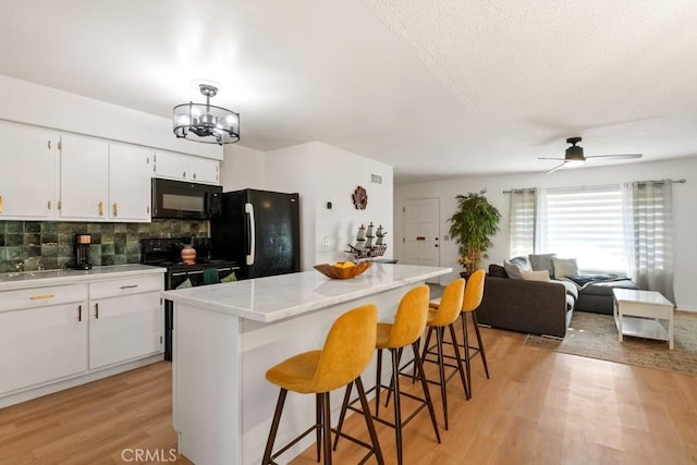 609 S Palm Ave Unit B, Hemet, CA 92543 - kitchen with black appliances, backsplash, light wood finished floors, a center island, and a kitchen breakfast bar