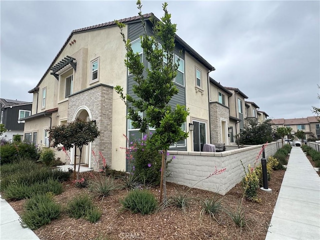 3641 E Moonlight St Unit 51, Ontario, CA 91761 - view of side of home featuring a residential view, stucco siding, and stone siding