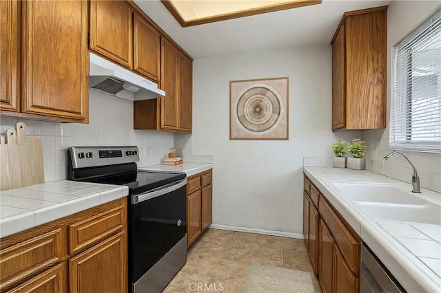 2820 W Devonshire Ave, Hemet, CA 92545 - kitchen featuring electric stove, under cabinet range hood, brown cabinetry, tasteful backsplash, and tile counters