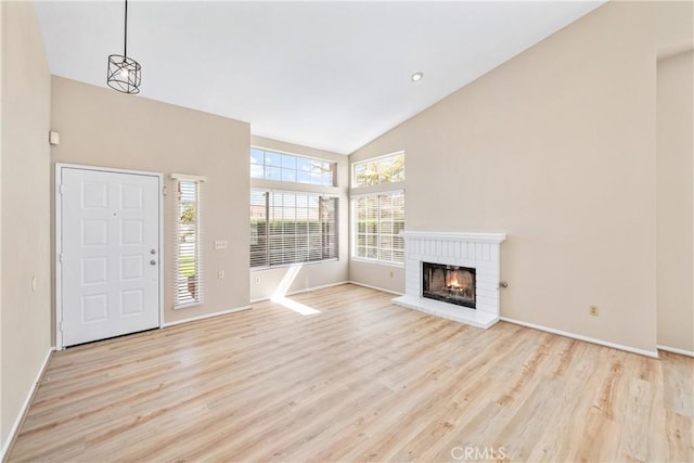 13073 San Dimas Cir, Victorville, CA 92392 - unfurnished living room with high vaulted ceiling, light wood-style flooring, baseboards, and a brick fireplace