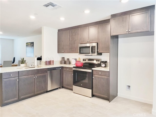209 Dylan St, Merced, CA 95341 - kitchen featuring stainless steel appliances, recessed lighting, dark brown cabinets, a peninsula, and light stone counters
