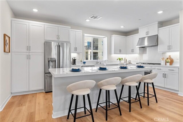 25 Splendor Way, Rancho Mission Viejo, CA 92694 - kitchen with under cabinet range hood, high end refrigerator, a breakfast bar area, a center island, and white cabinetry
