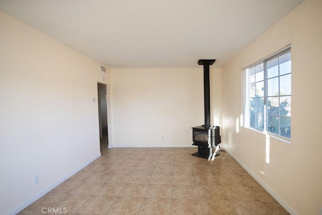 58382 Sunny Sands Dr, Yucca Valley, CA 92284 - unfurnished living room featuring a wood stove, light tile patterned flooring, and baseboards