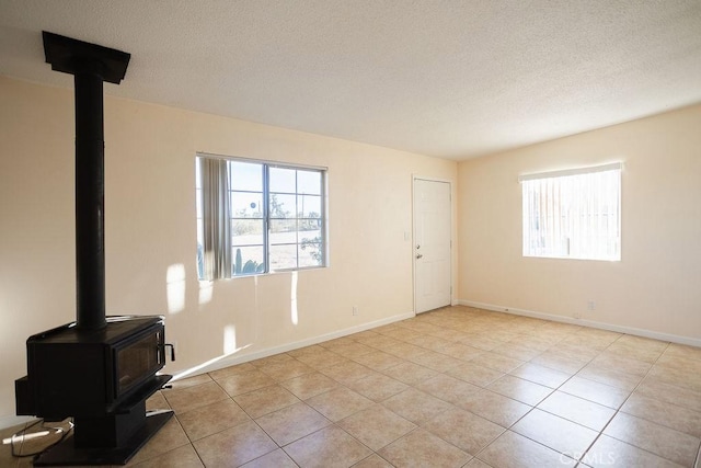 58382 Sunny Sands Dr, Yucca Valley, CA 92284 - unfurnished living room with a wood stove, light tile patterned flooring, a textured ceiling, and baseboards