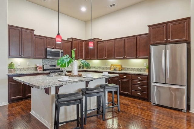 25863 Prospector Ct, Menifee, CA 92584 - kitchen with stainless steel appliances, a high ceiling, dark wood-type flooring, a center island with sink, and pendant lighting