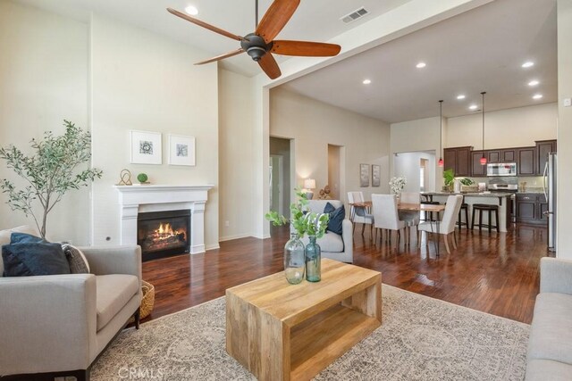 25863 Prospector Ct, Menifee, CA 92584 - living area with ceiling fan, dark wood-style flooring, a glass covered fireplace, recessed lighting, and a towering ceiling