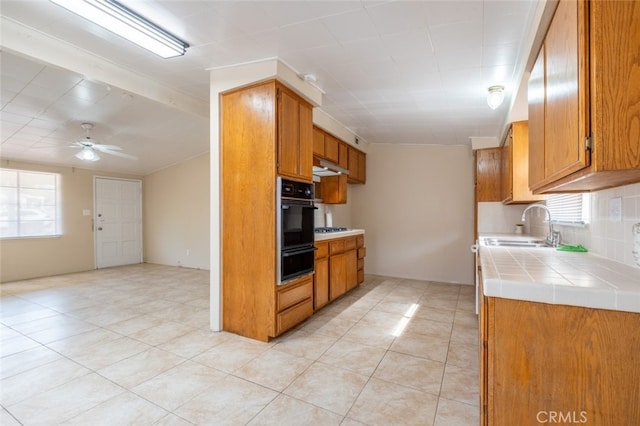 39026 11th St W, Palmdale, CA 93551 - kitchen with black oven, a sink, a warming drawer, tile counters, and light tile patterned flooring
