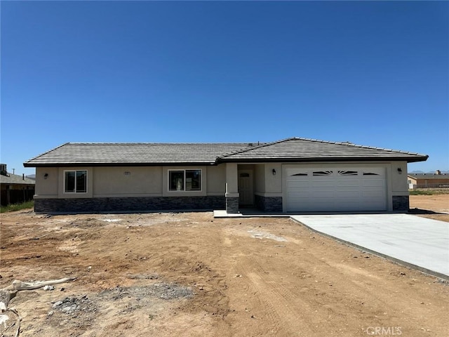 15731 Sago Rd, Apple Valley, CA 92307 - view of front facade featuring stone siding, a garage, driveway, stucco siding, and a tiled roof