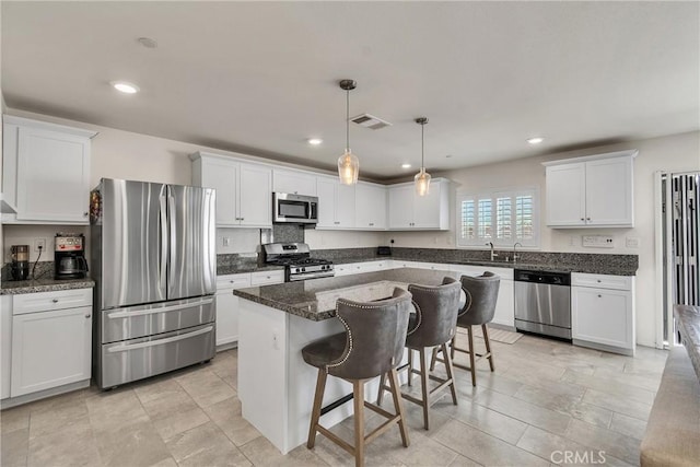 15040 Capstone St, Fontana, CA 92336 - kitchen featuring appliances with stainless steel finishes, a sink, white cabinetry, a kitchen bar, and a kitchen island