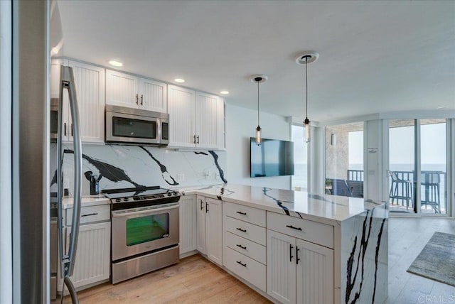 190 Del Mar Shores Ter Unit 24, Solana Beach, CA 92075 - kitchen featuring stainless steel appliances, a peninsula, decorative backsplash, light wood-style floors, and light stone counters