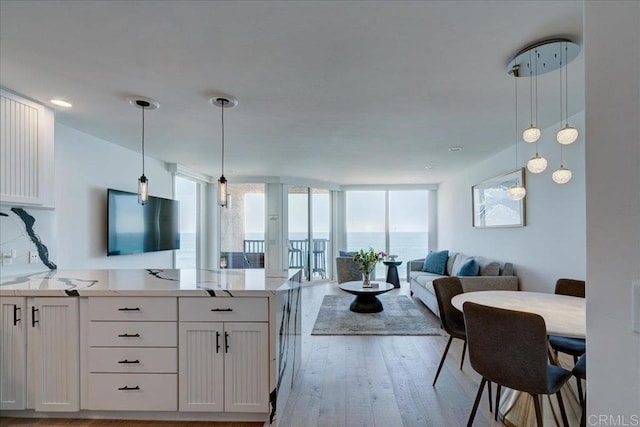 190 Del Mar Shores Ter Unit 24, Solana Beach, CA 92075 - kitchen with open floor plan, light wood finished floors, a peninsula, white cabinetry, and a wall of windows