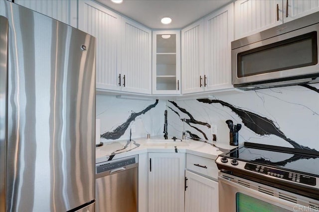 190 Del Mar Shores Ter Unit 24, Solana Beach, CA 92075 - kitchen featuring appliances with stainless steel finishes, white cabinets, glass insert cabinets, backsplash, and light stone counters