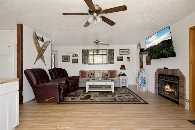 26249 Cedar Ln, Twin Peaks, CA 92391 - living room with light wood-style flooring, a ceiling fan, a textured ceiling, and a fireplace