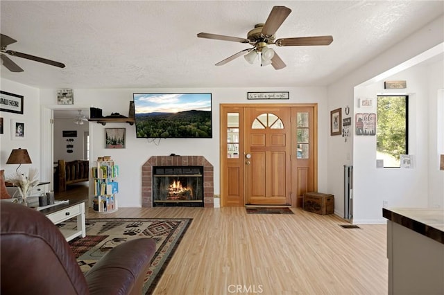 26249 Cedar Ln, Twin Peaks, CA 92391 - living room with a ceiling fan, light wood-style flooring, a textured ceiling, and a fireplace