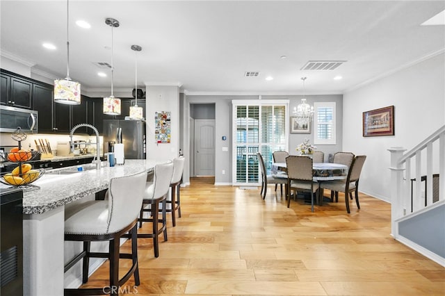 22124 Barrington Way, Saugus, CA 91350 - kitchen with appliances with stainless steel finishes, ornamental molding, dark cabinetry, baseboards, and light wood-type flooring
