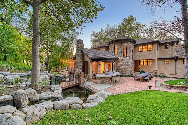 31742 Contijo Way, Coto De Caza, CA 92679 - rear view of house featuring stone siding, a patio area, a chimney, a lawn, and stucco siding