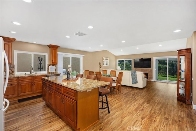 28052 Espinoza, Mission Viejo, CA 92692 - kitchen featuring a kitchen bar, open floor plan, brown cabinets, a center island, and light wood-style flooring