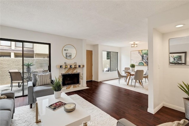 849 E Victoria St Unit 210, Carson, CA 90746 - living room featuring healthy amount of natural light, wood finished floors, a textured ceiling, baseboards, and a fireplace with flush hearth
