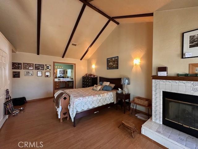 2968 Mill Creek Rd, Mentone, CA 92359 - bedroom featuring wood finished floors, a fireplace, beam ceiling, baseboards, and high vaulted ceiling