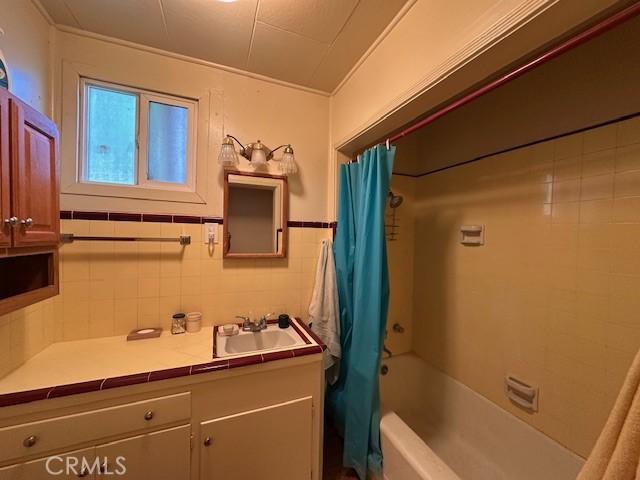 2968 Mill Creek Rd, Mentone, CA 92359 - full bath with shower / tub combo with curtain, vanity, and tile walls