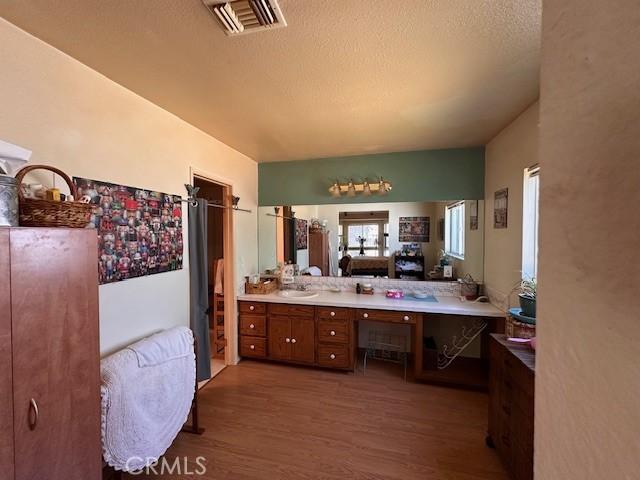 2968 Mill Creek Rd, Mentone, CA 92359 - full bathroom featuring wood finished floors, a textured ceiling, vanity, and a shower with shower curtain