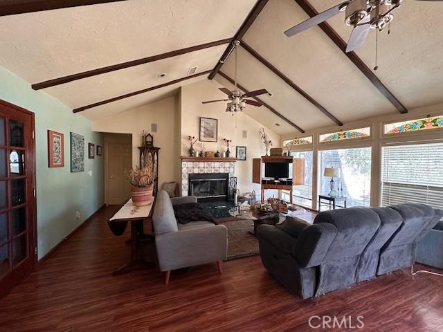 2968 Mill Creek Rd, Mentone, CA 92359 - living area with a ceiling fan, wood finished floors, beamed ceiling, a tiled fireplace, and high vaulted ceiling