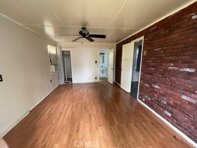 2968 Mill Creek Rd, Mentone, CA 92359 - spare room featuring wood finished floors, ceiling fan, and brick wall