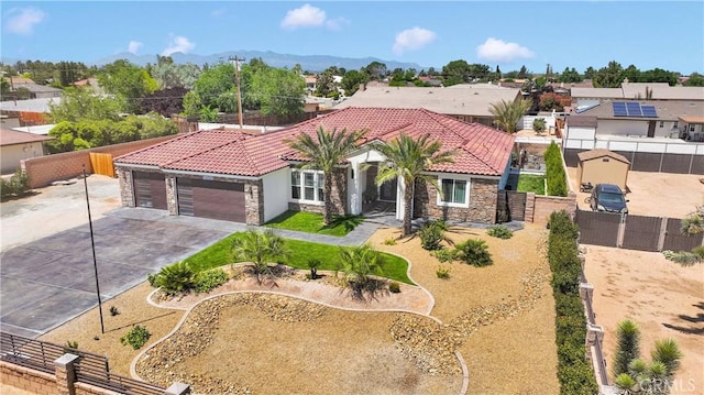 14258 Crow Rd, Apple Valley, CA 92307 - mediterranean / spanish house featuring stone siding, a tiled roof, an attached garage, concrete driveway, and a residential view