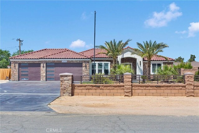 14258 Crow Rd, Apple Valley, CA 92307 - view of front of property featuring a tiled roof, a fenced front yard, stone siding, an attached garage, and driveway