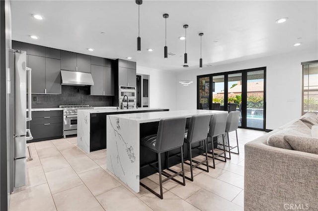 14258 Crow Rd, Apple Valley, CA 92307 - kitchen with appliances with stainless steel finishes, a center island with sink, open floor plan, under cabinet range hood, and light countertops