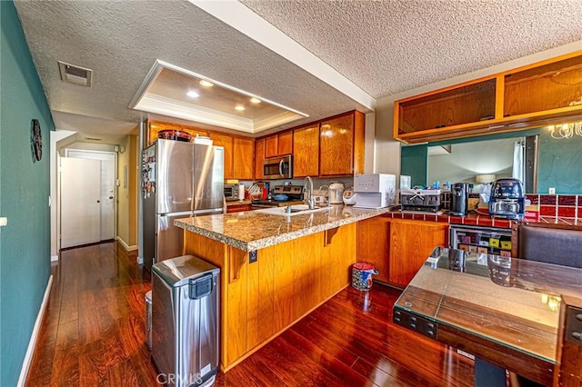 1130 Whitewater Dr Unit 263, Fullerton, CA 92833 - kitchen with a textured ceiling, appliances with stainless steel finishes, brown cabinetry, a sink, and a raised ceiling