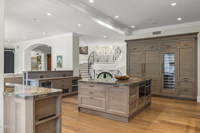 2112 Trentham Rd, Triunfo Pass-Point Mugu, CA 91361 - kitchen with a center island, ornamental molding, dark stone countertops, light wood-style flooring, and arched walkways