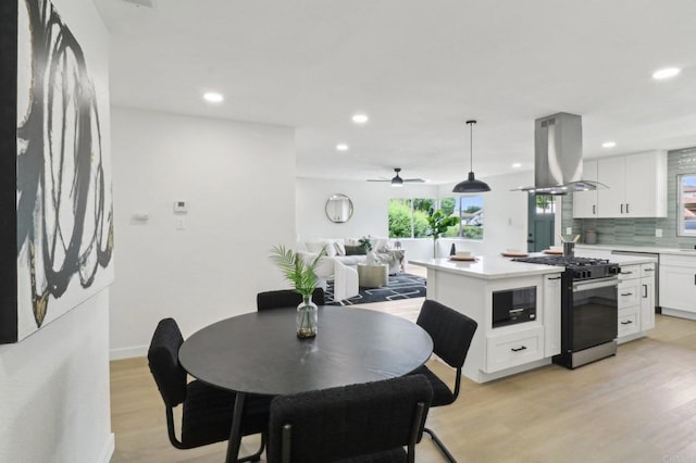 3243 Carolyn Cir, Oceanside, CA 92054 - kitchen with island exhaust hood, gas range, light countertops, light wood finished floors, and white cabinets